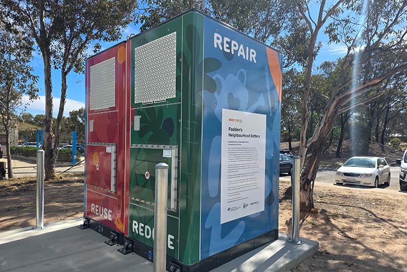 Close up of Fadden Battery with red, blue and green artwork on a concrete pad and backed by gum trees.