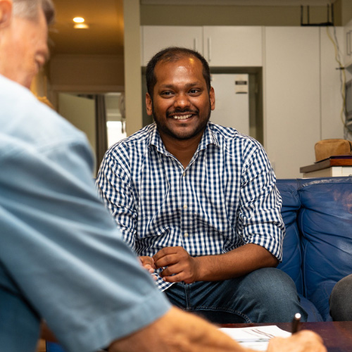 Sai Ram, smiling, looks across a coffee table at Jeff, the energy assessor.